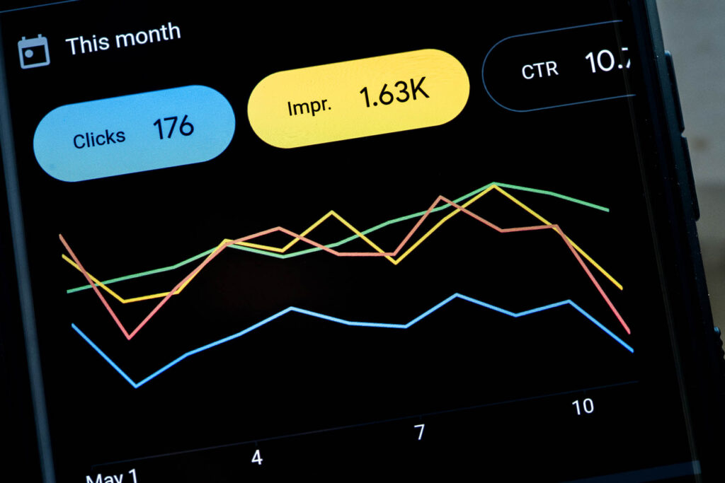 Google Ads app dashboard interface on a mobile device smartphone showing clicks impressions CTR and ad campaign cost line charts for a month, digital marketing concept